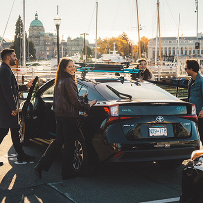 Friends getting into an Evo with Victoria's parliament building in the background