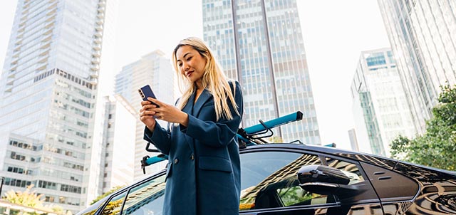 Woman on phone in city in front of a parked Evo