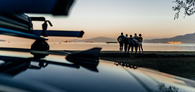 Friends on a beach at sunset with the roof of an Evo in the foreground