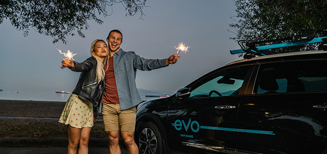 Two people holding sparklers standing near a beach at night